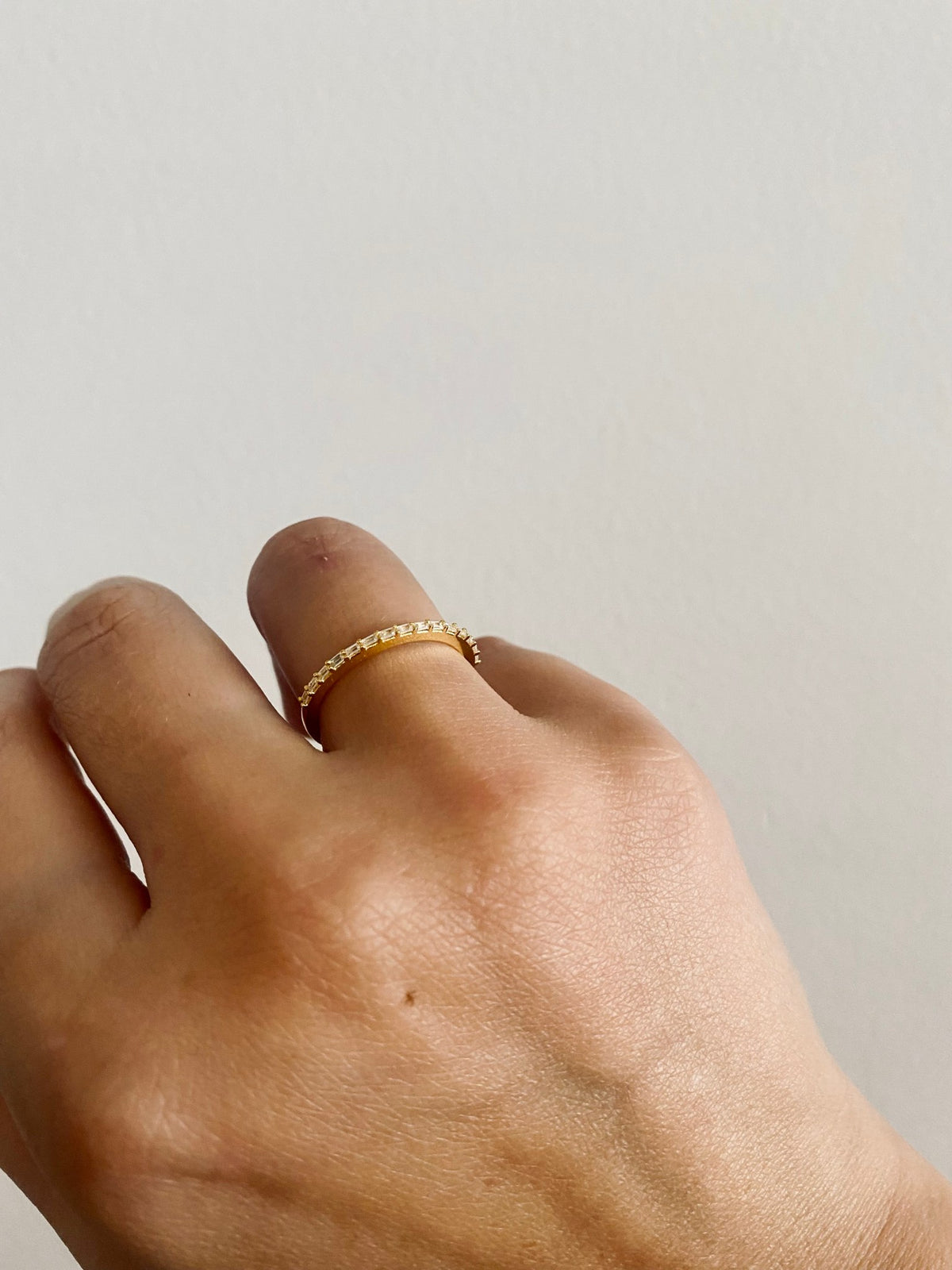 Dainty baguette diamond wedding band close up on hand