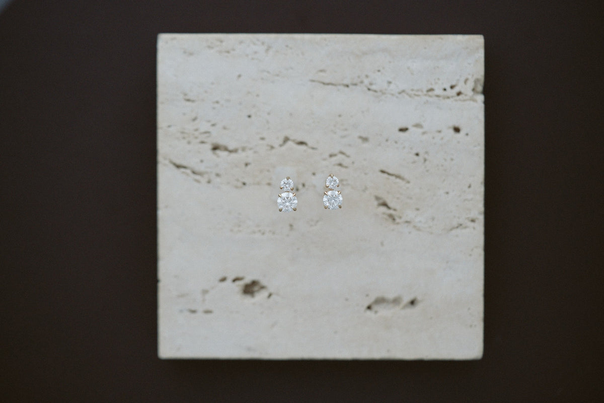 Horizon Diamond Earrings by Lane & Kate, two stone diamond studs styled on travertine