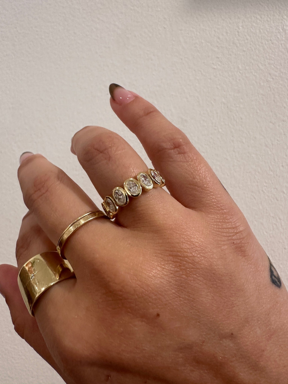 Oval Demur wedding band in 14kt yellow gold with bezel set oval diamonds worn on the hand