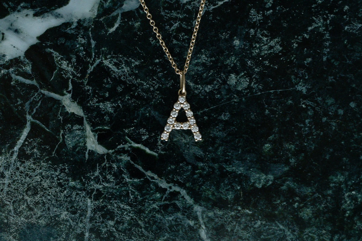 Diamond Initial Necklace, petite diamond letter A in 14kt yellow gold on green marble