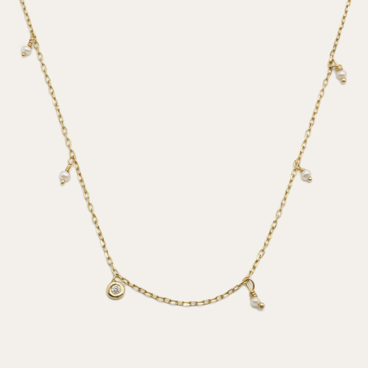 Pearl Shaker Necklace by Gjenmi, 14kt yellow gold diamond cut chain with freshwater pearls and a bezel set white diamond