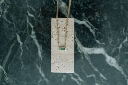Zoe Chicco Emerald Bezel Set Curb Chain in 14kt yellow gold draped over travertine on green marble