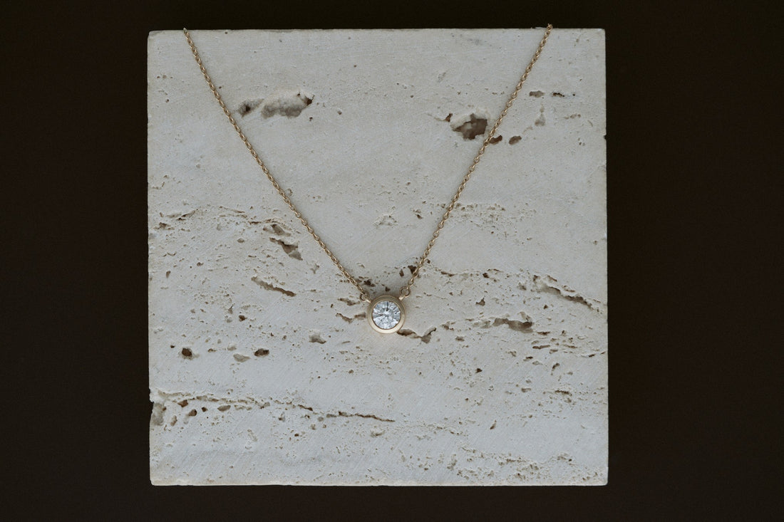 Heirloom Deity Pendant draped over travertine on a dark background
