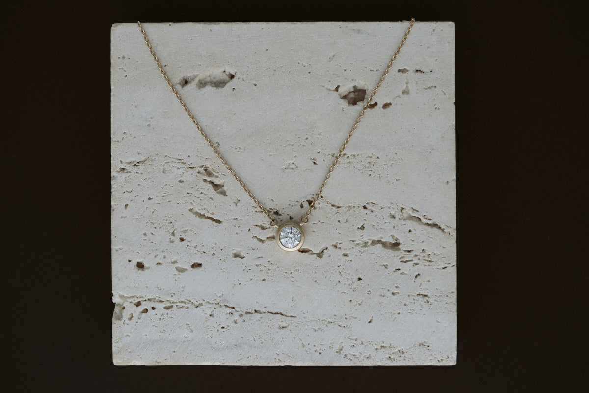 Heirloom Deity Pendant draped over travertine on a dark background