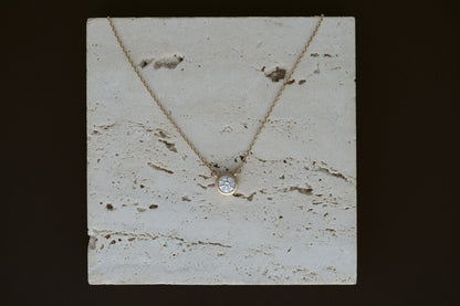 Heirloom Deity Pendant draped over travertine on a dark background