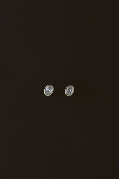 Oval Damsel Studs, bezel set oval diamond earrings in 14kt yellow gold on a dark background