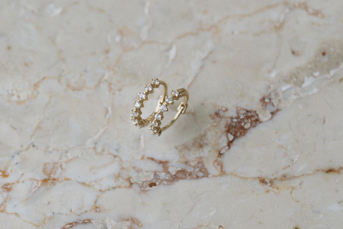 Compass Guides Huggies by Lane &amp; Kate in 14kt yellow gold with diamonds, on marble