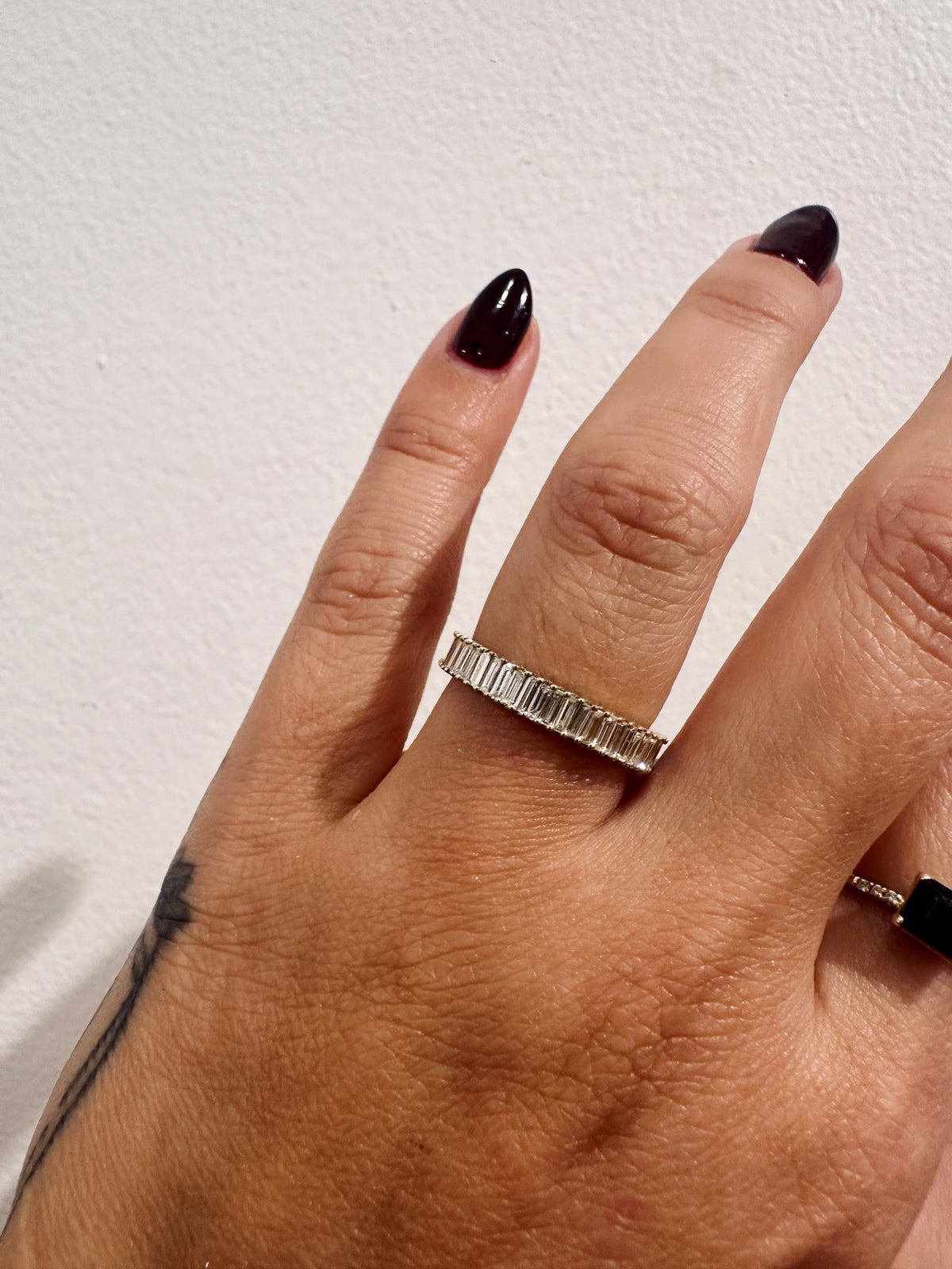 Vertical baguette diamond wedding band on hand, side angle