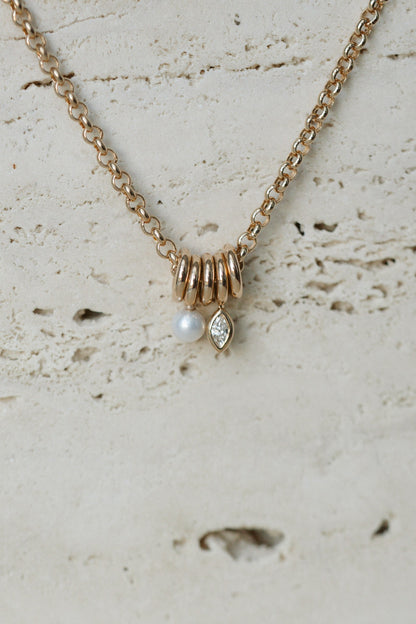 Zoe Chicco Mixed Rings Diamond Necklace in 14kt yellow gold with five gold rings, a round diamond and a marquise diamond on travertine