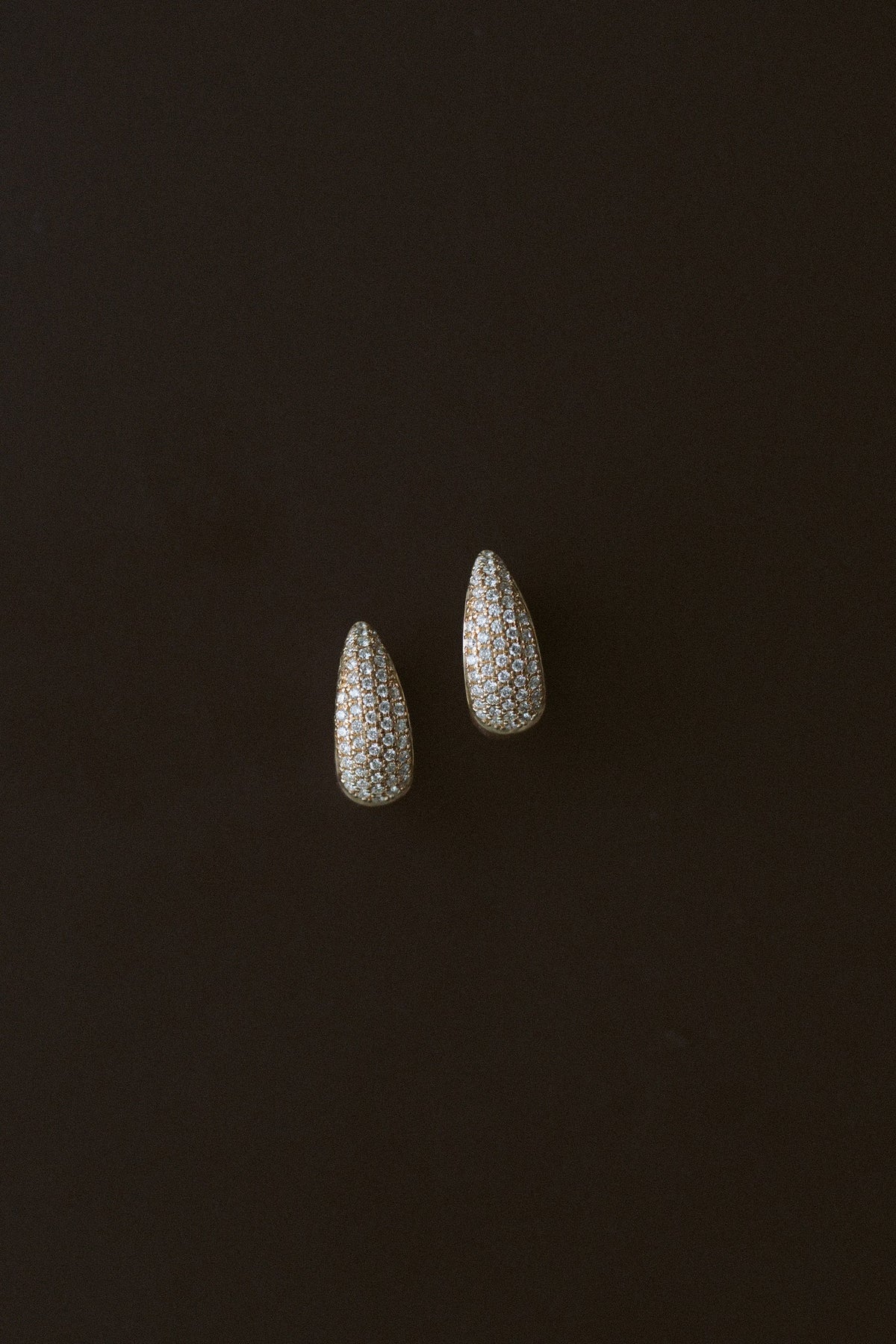 Demur Pavé Hoops, domed natural diamond pavé hoops in 14kt yellow gold on a dark background