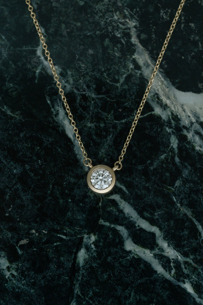 Heirloom Deity Pendant, bezel set round diamond necklace in 14kt yellow gold on green marble