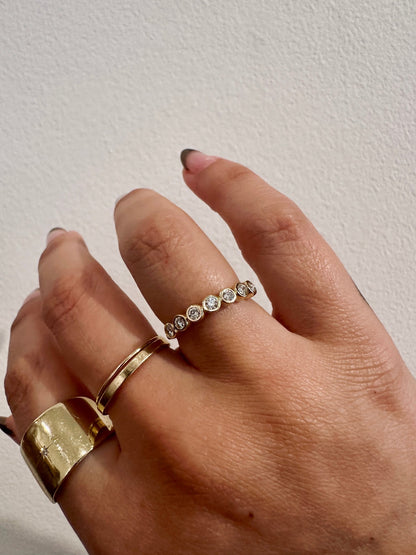 Diamond Deity wedding band in 14kt yellow gold with bezel set round diamonds worn on the hand