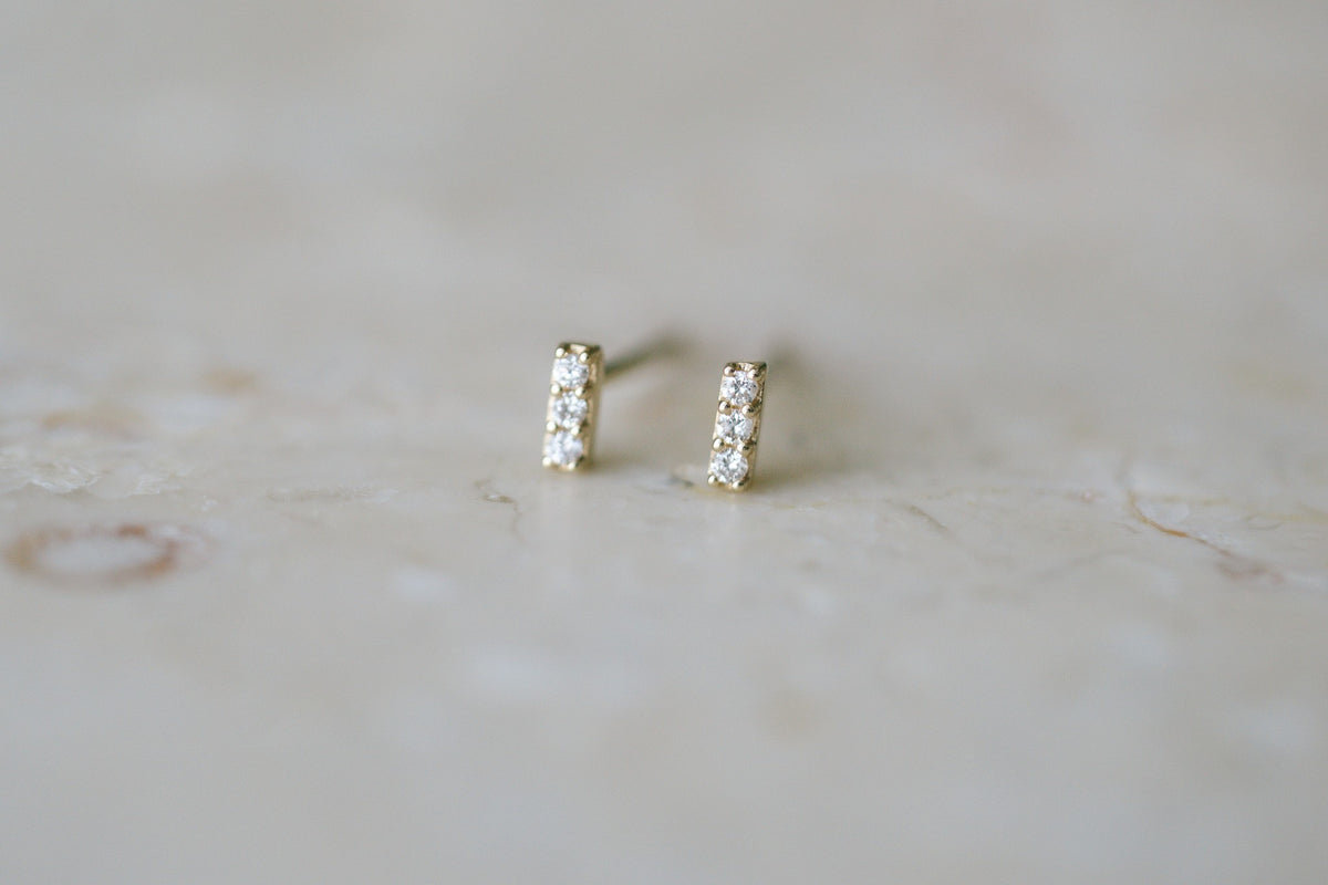 BB Three Diamond Bars, a pair of diamond bar studs in 14kt yellow gold on stone, close up