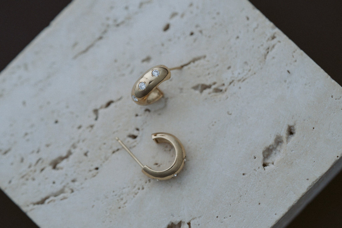 3 Diamond Chubby Huggies by Zoe Chicco in 14kt yellow gold, styled on travertine stone