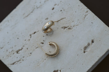 3 Diamond Chubby Huggies by Zoe Chicco in 14kt yellow gold, styled on travertine stone