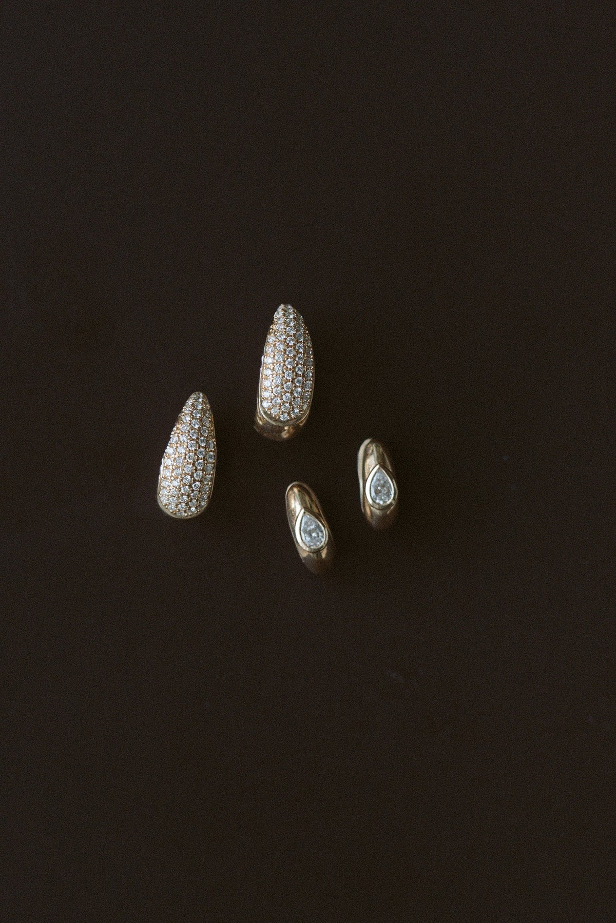 Demur Pavé Hoops in 14kt yellow gold with a pair of diamond studs on a dark background