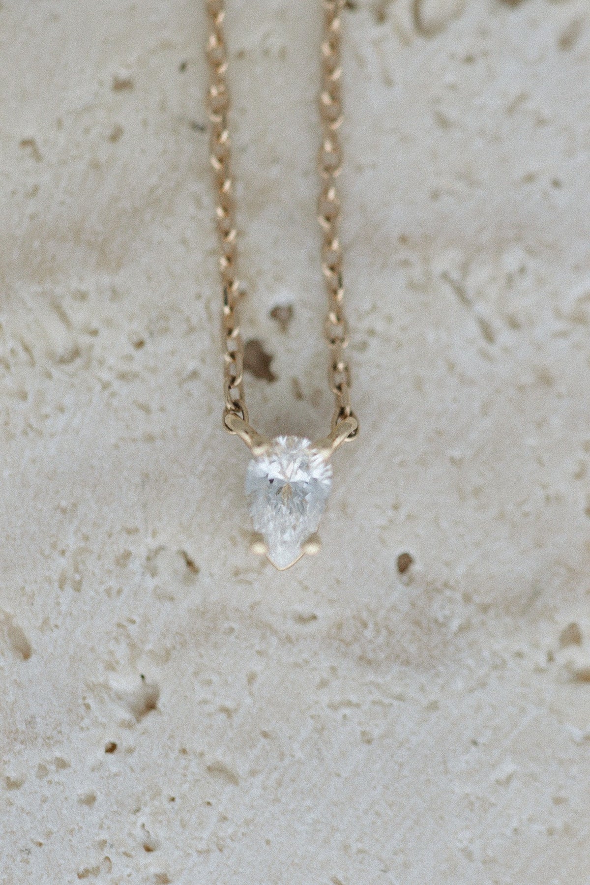 Tear of Cupid Pendant on travertine, close up of the pear diamond
