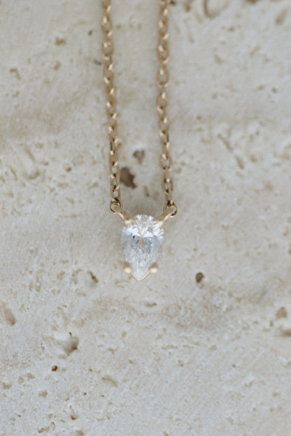 Tear of Cupid Pendant on travertine, close up of the pear diamond