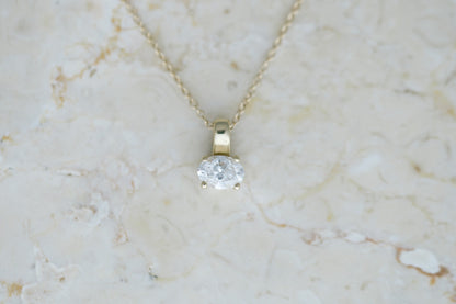 Oval Prism Necklace, a four prong oval diamond on a 14kt yellow gold cable chain on travertine