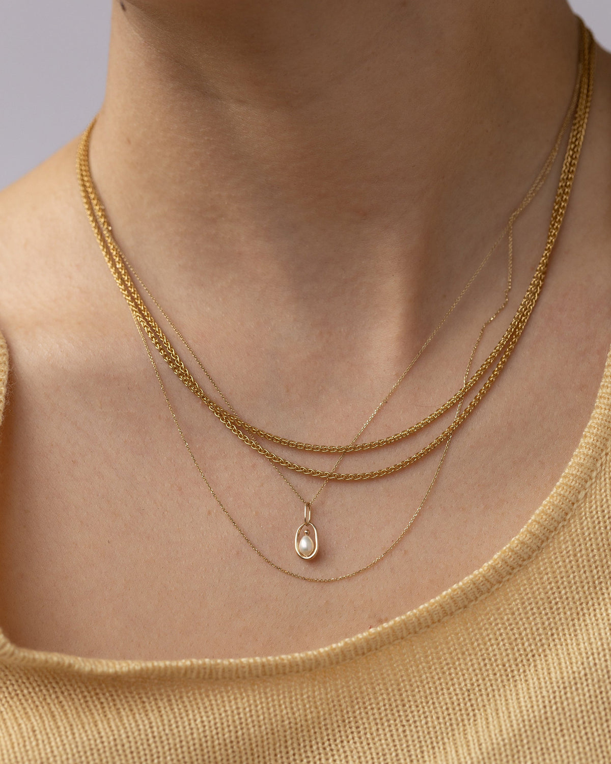Pearl Droplet Pendant layered with gold chains, worn
