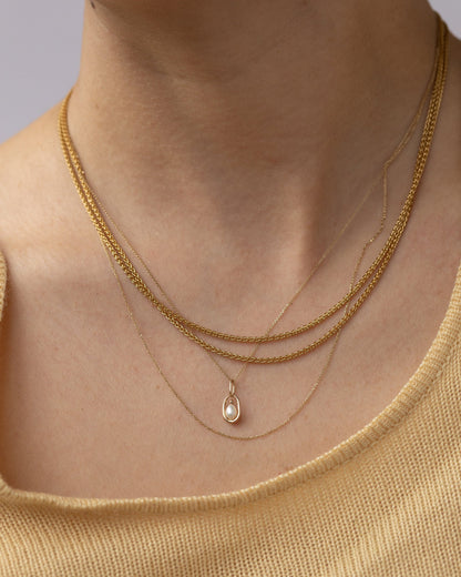 Pearl Droplet Pendant layered with gold chains, worn
