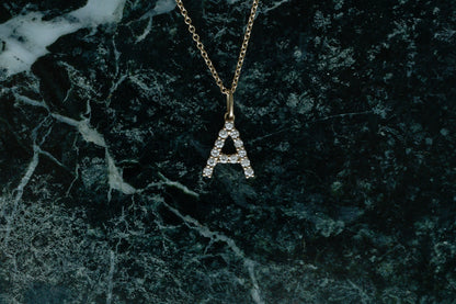 Diamond Initial Necklace, petite diamond letter A in 14kt yellow gold on green marble