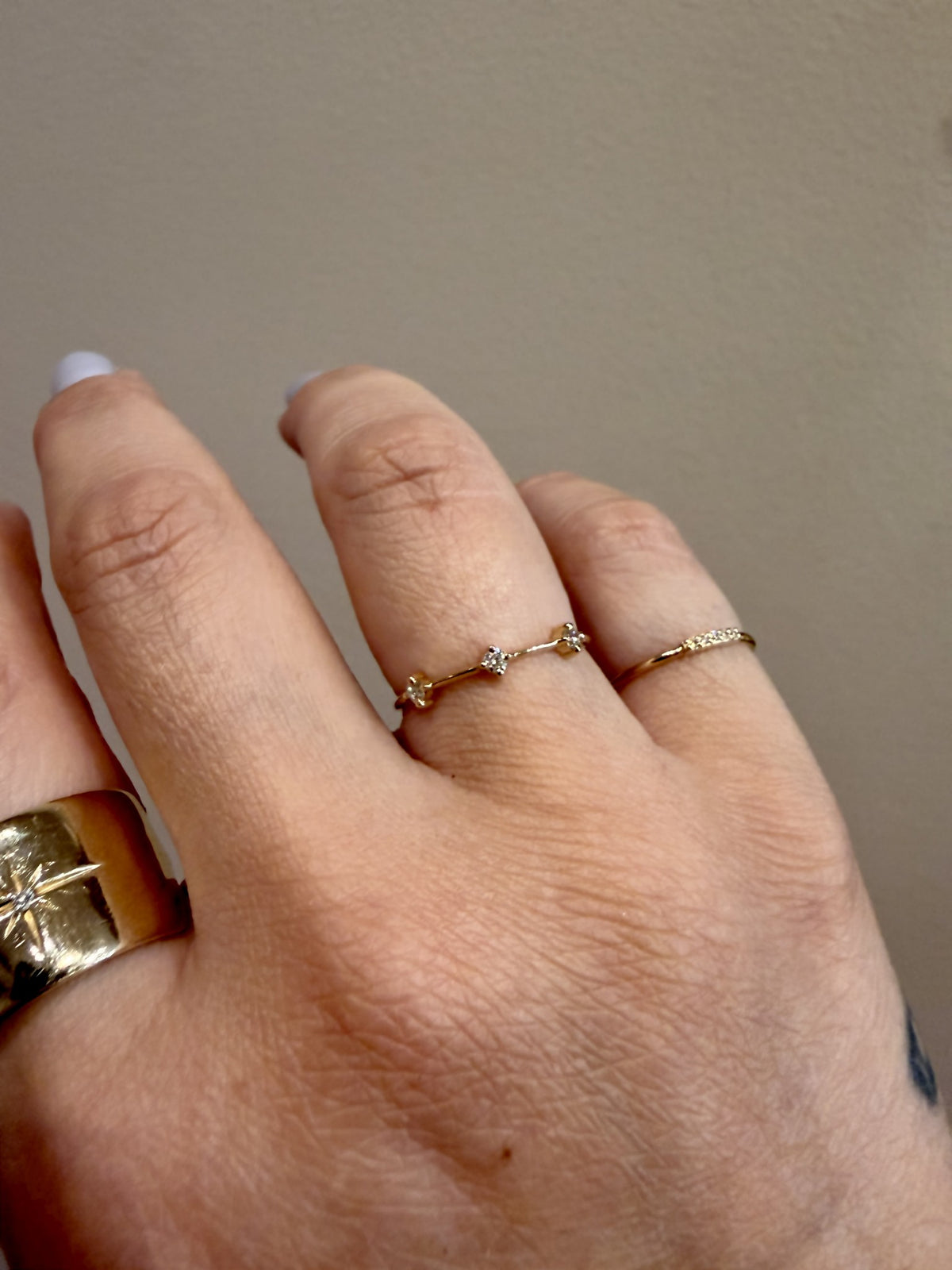 3 Prong Diamond Dash Ring with three prong set diamonds in 14kt yellow gold worn on the hand