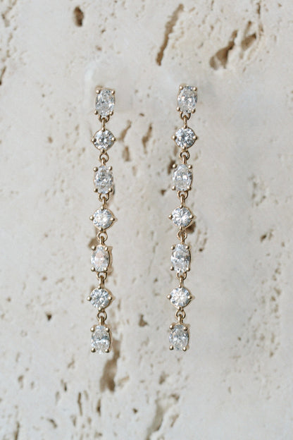 Glimmer Diamond Drops, diamond line drop earrings in 14kt yellow gold on travertine