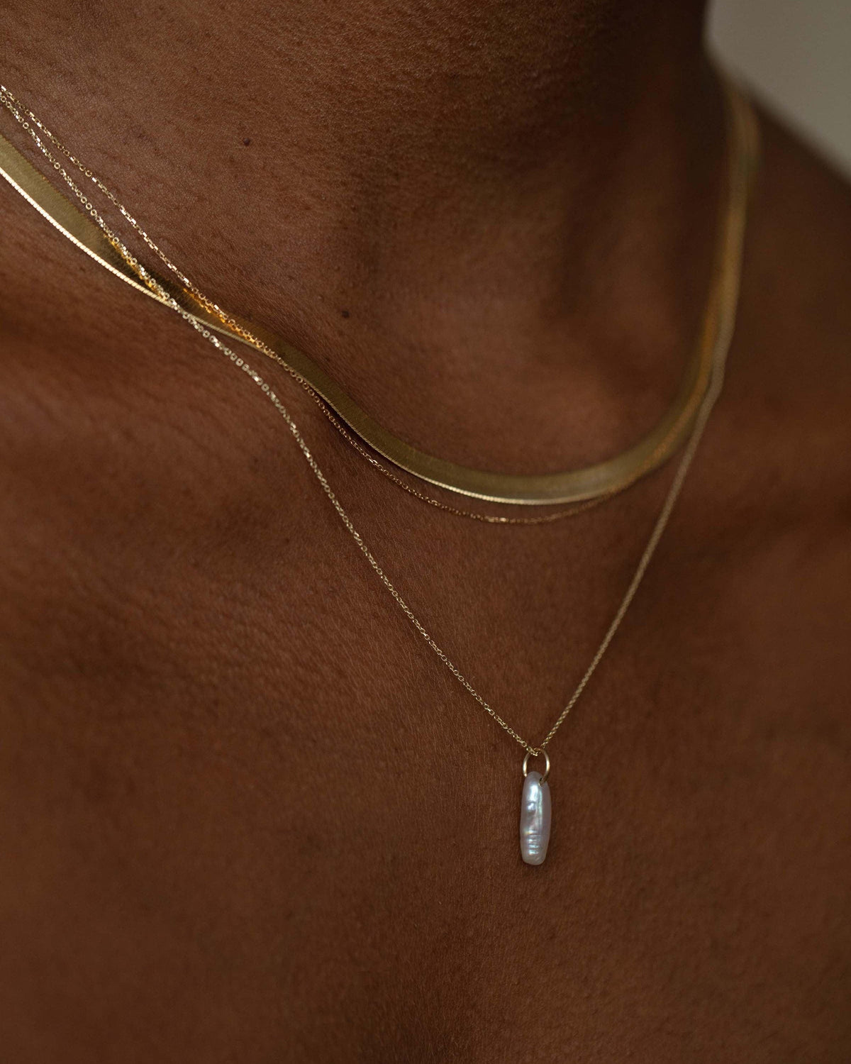 Lagniappe Pearl Charm layered with gold chains, worn