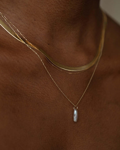 Lagniappe Pearl Charm layered with gold chains, worn