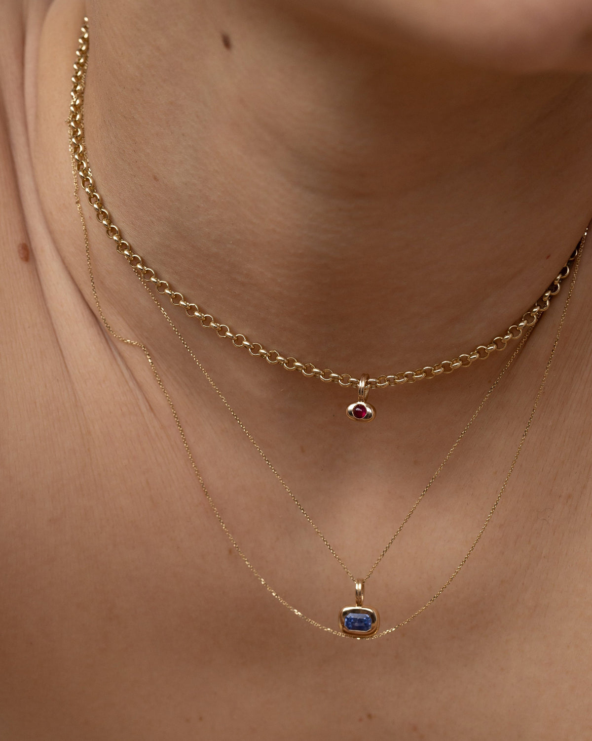 Tempo birthstone pendants layered on a gold chain, worn