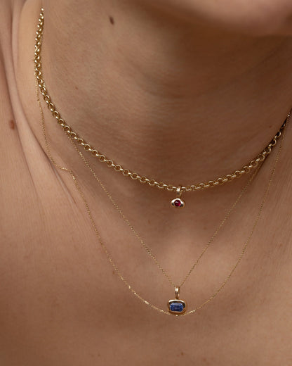 Tempo birthstone pendants layered on a gold chain, worn