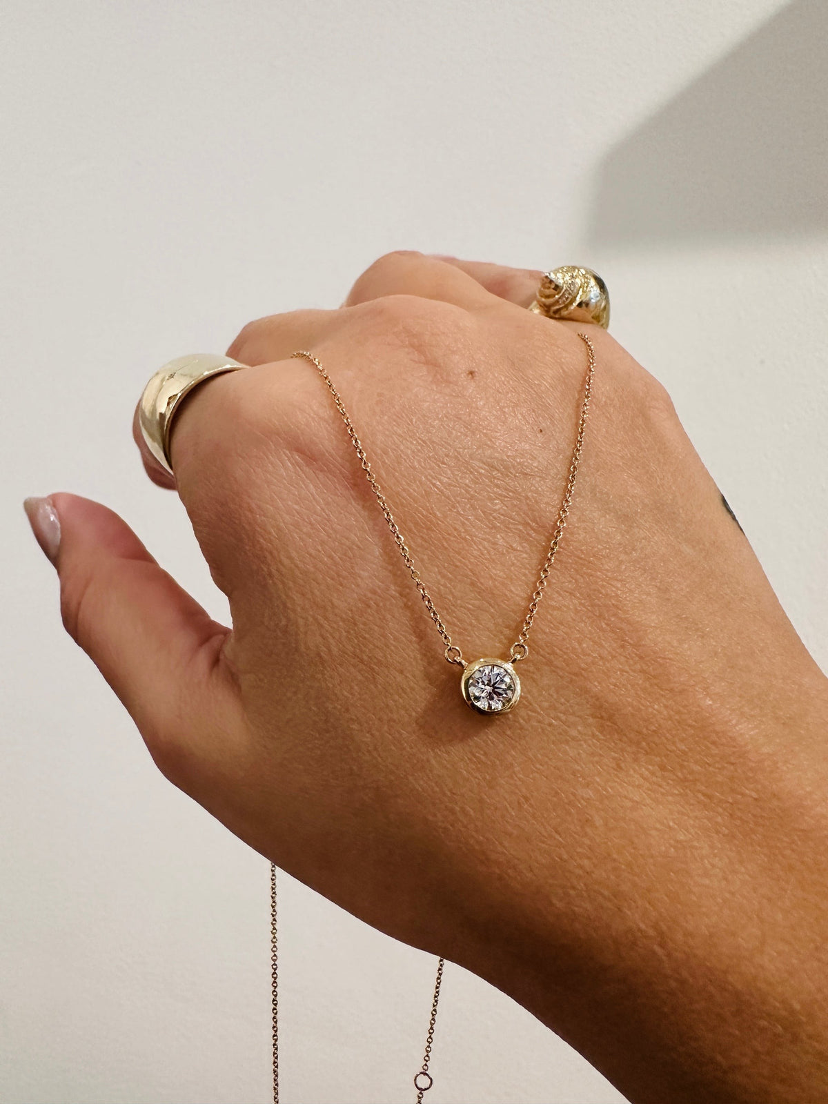Heirloom Deity Pendant, bezel set round diamond necklace draped over the hand