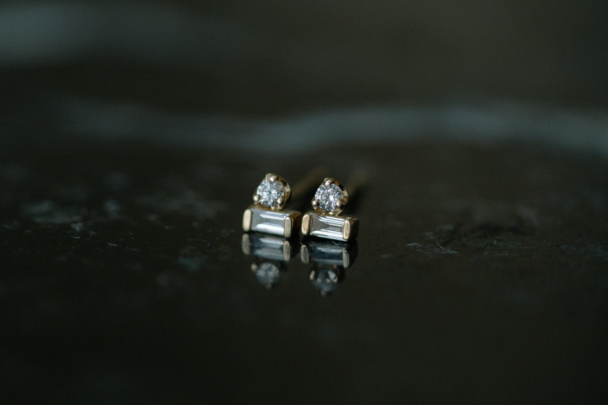 Zoe Chicco Baguette &amp; Prong Diamond Stacked Studs in 14kt yellow gold, a round diamond stacked on a baguette, on dark stone