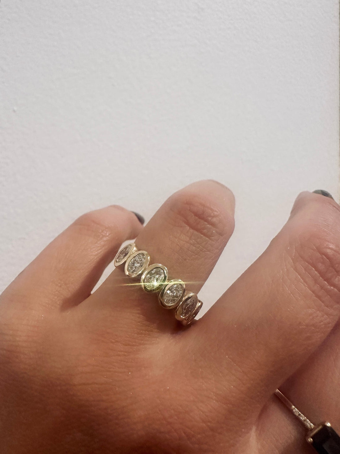 Oval Demur wedding band in 14kt yellow gold with bezel set oval diamonds worn on the hand