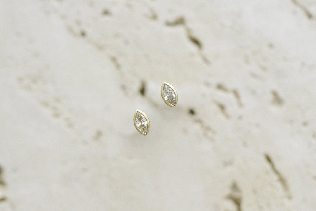 BB Marquise Dew Drops, bezel set marquise diamond studs in 14kt yellow gold on travertine