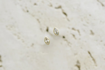 BB Marquise Dew Drops, bezel set marquise diamond studs in 14kt yellow gold on travertine