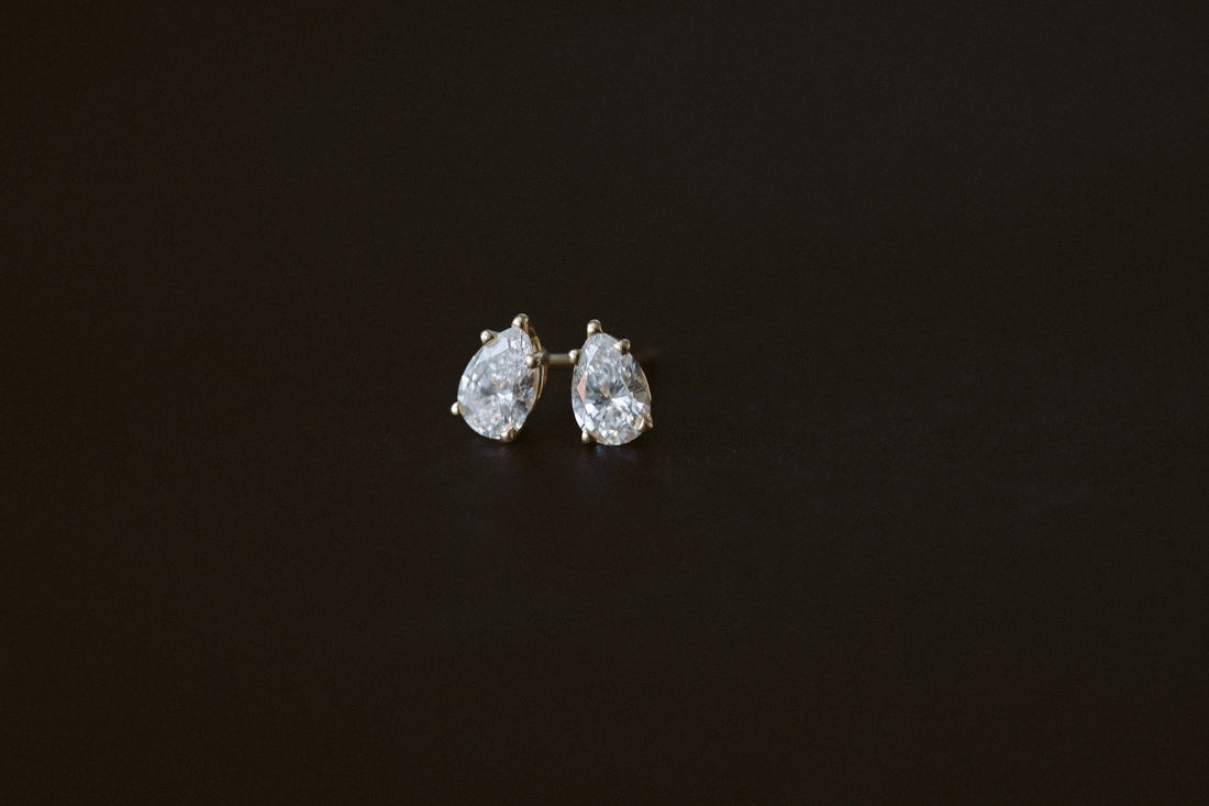BB Prong Pear Dew Drops, pear diamond studs in 14kt yellow gold on a dark background