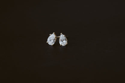 BB Prong Pear Dew Drops, pear diamond studs in 14kt yellow gold on a dark background