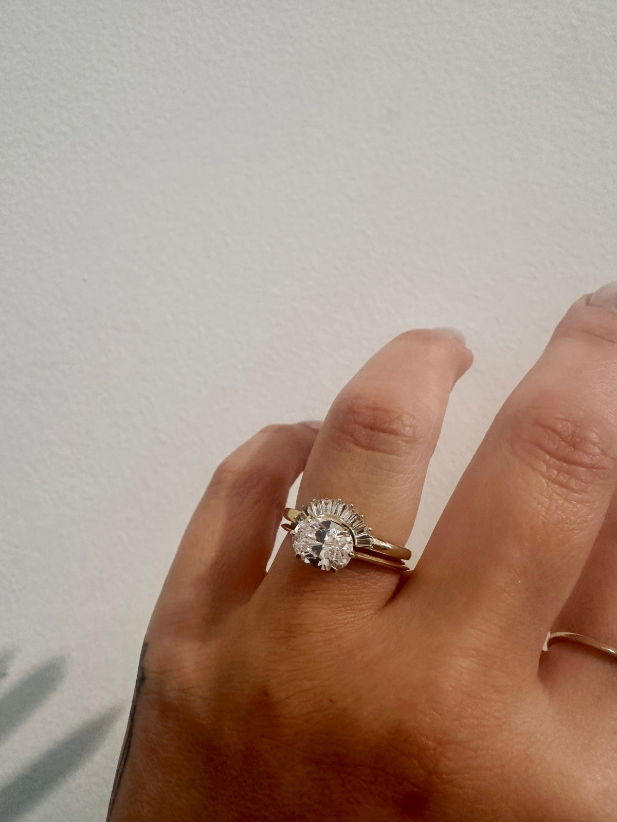 Baguette Rivers Contour Wedding Band with an oval engagement ring on hand